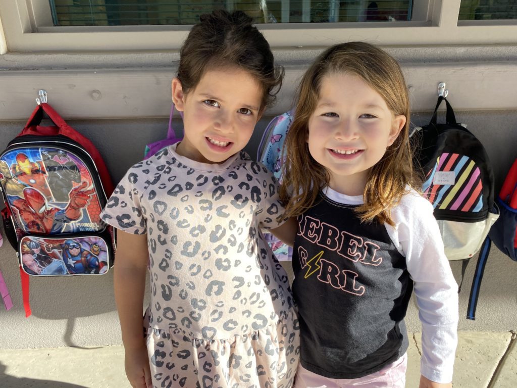 Young girls smiling by backpacks